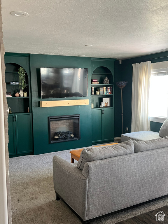 Living room with a textured ceiling, a fireplace, and built in shelves