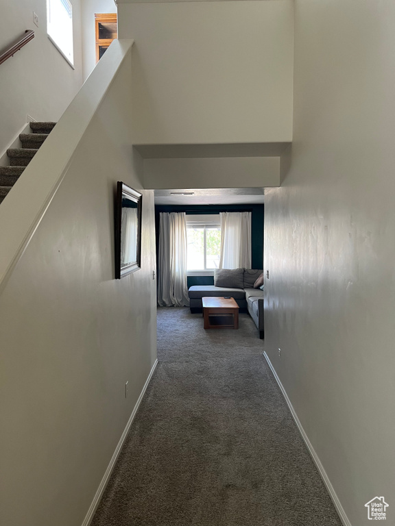 Corridor with baseboards, carpet flooring, a high ceiling, and stairway