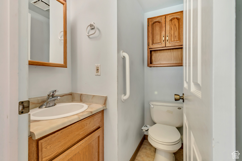 Half bath featuring vanity, visible vents, toilet, baseboards, and tile patterned floors