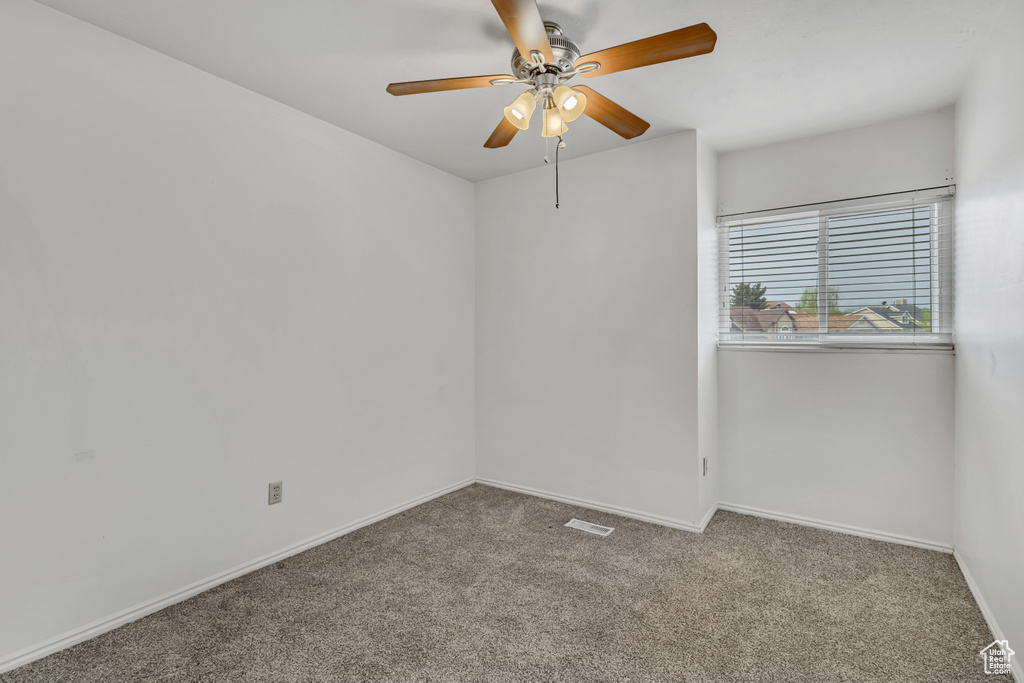Carpeted empty room with visible vents, baseboards, and ceiling fan