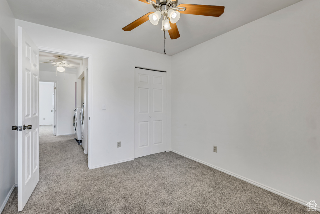 Unfurnished bedroom with carpet floors, baseboards, washer and dryer, and a closet