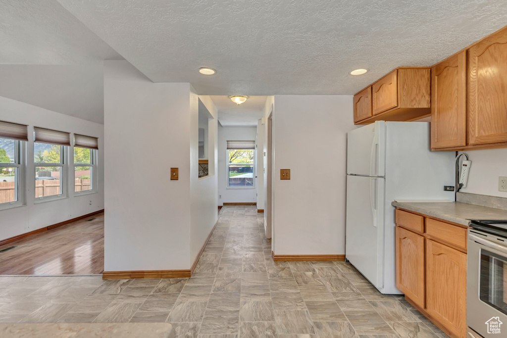 Kitchen featuring baseboards, a textured ceiling, stainless steel electric range, and a healthy amount of sunlight