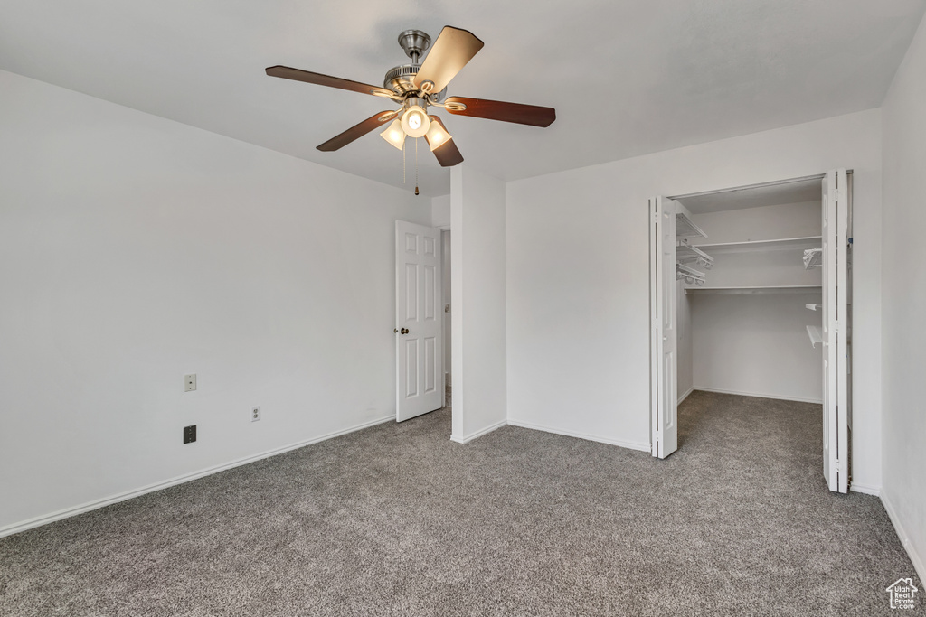 Unfurnished bedroom featuring ceiling fan, carpet, baseboards, a spacious closet, and a closet