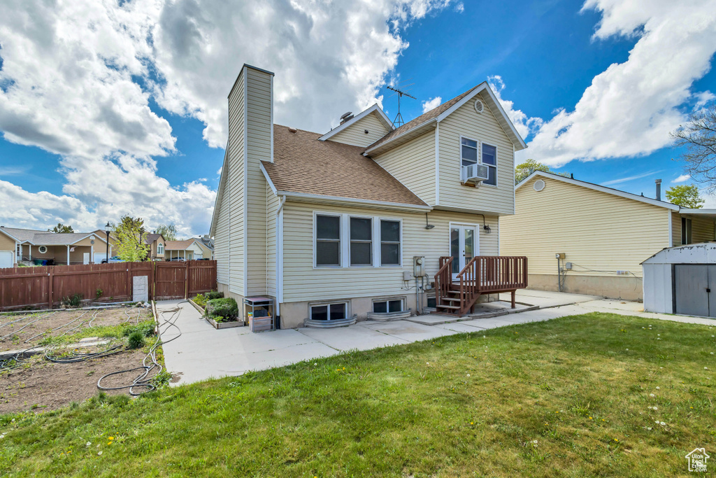 Back of house featuring fence, a shed, a chimney, a patio, and a yard