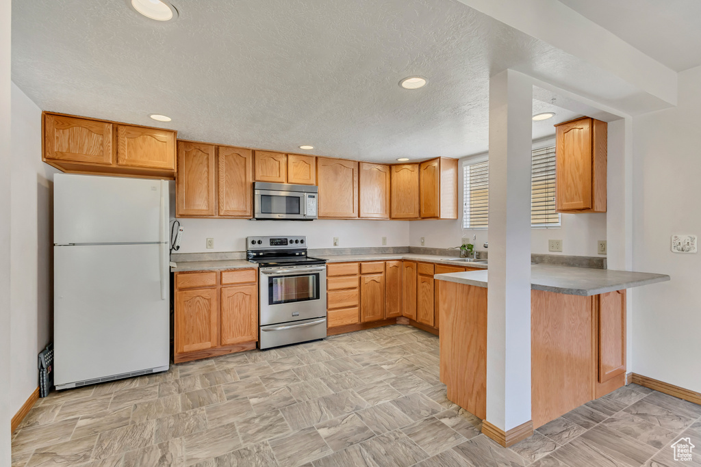Kitchen with recessed lighting, a peninsula, baseboards, and appliances with stainless steel finishes