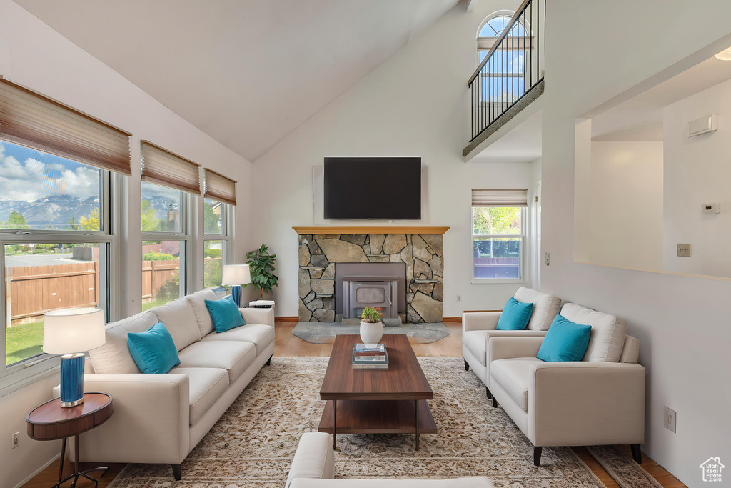 Living area featuring baseboards, a fireplace, wood finished floors, and high vaulted ceiling
