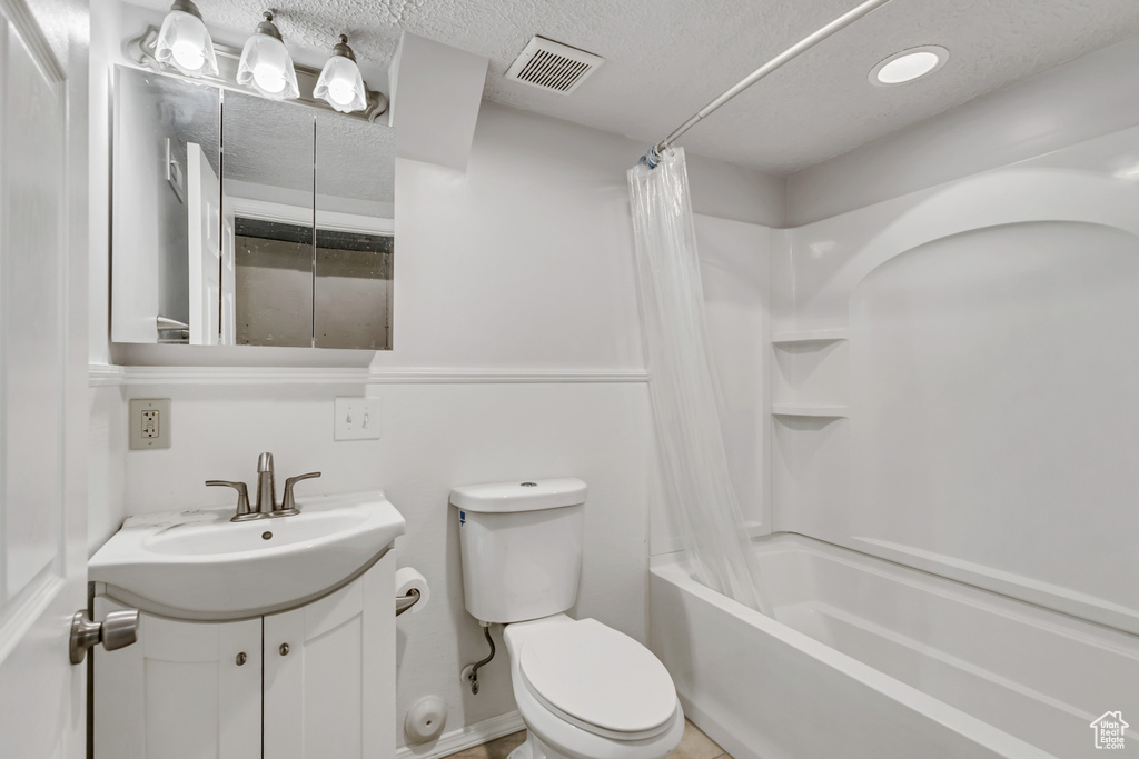 Full bathroom featuring visible vents, vanity, toilet, a textured ceiling, and shower / bath combo