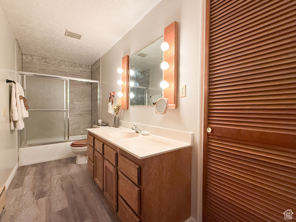 Full bathroom featuring wood finished floors, visible vents, toilet, a closet, and a textured ceiling