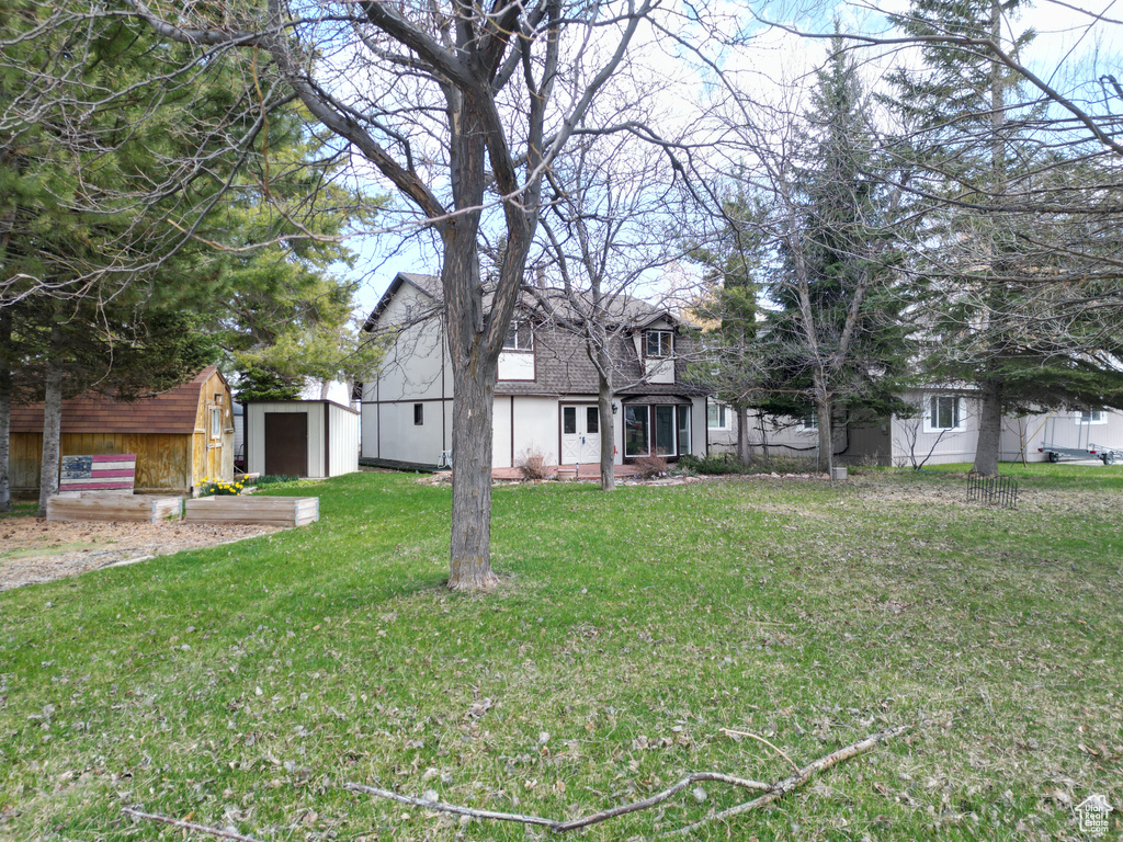 Exterior space featuring a shingled roof, an outdoor structure, a storage shed, and a front yard