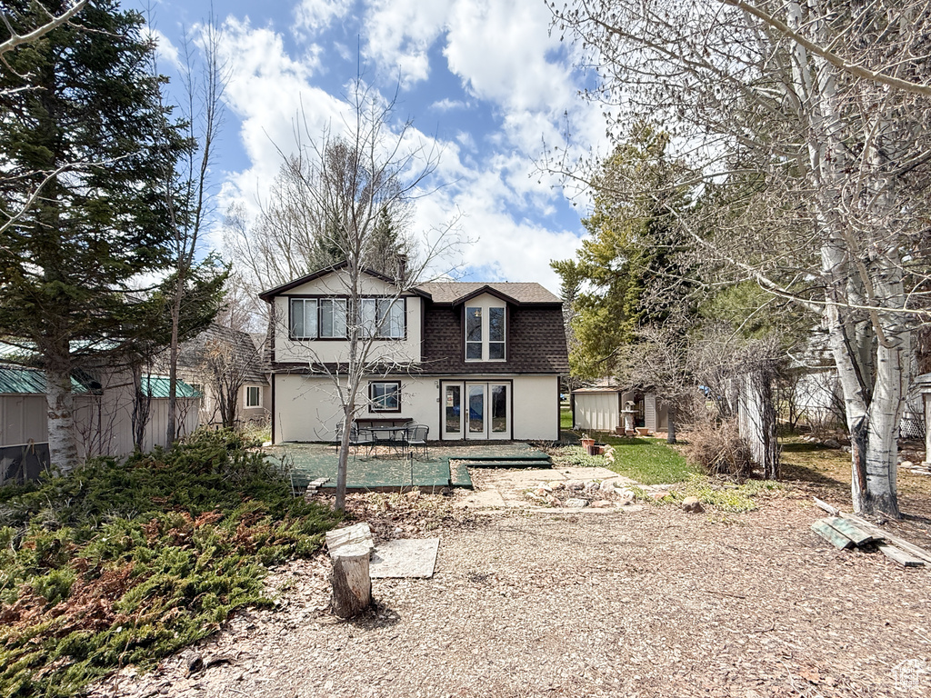 Back of property featuring french doors, roof with shingles, and stucco siding