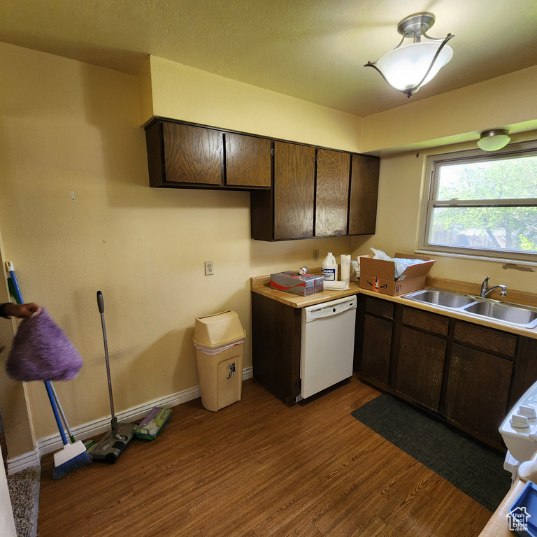 Kitchen with a sink, dark brown cabinets, dark wood-type flooring, and dishwasher