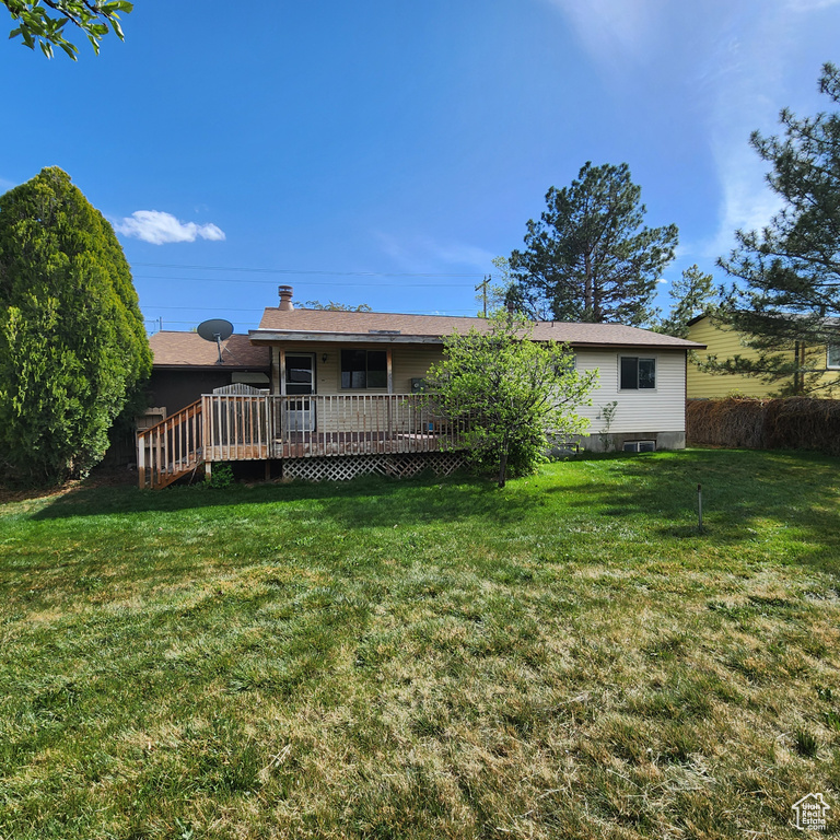 Back of property featuring a yard, a deck, and a chimney