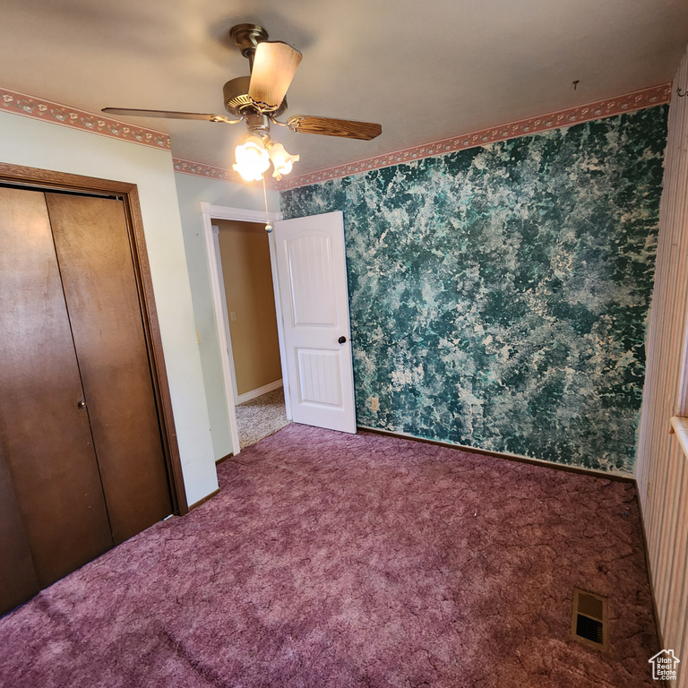 Unfurnished bedroom featuring carpet floors, ceiling fan, visible vents, and a closet
