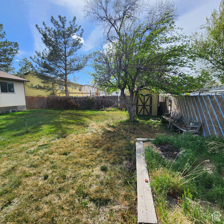 View of yard with a storage shed, an outdoor structure, and a fenced backyard