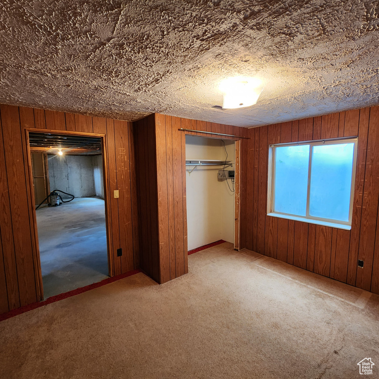 Unfurnished bedroom with wood walls, a closet, and carpet flooring