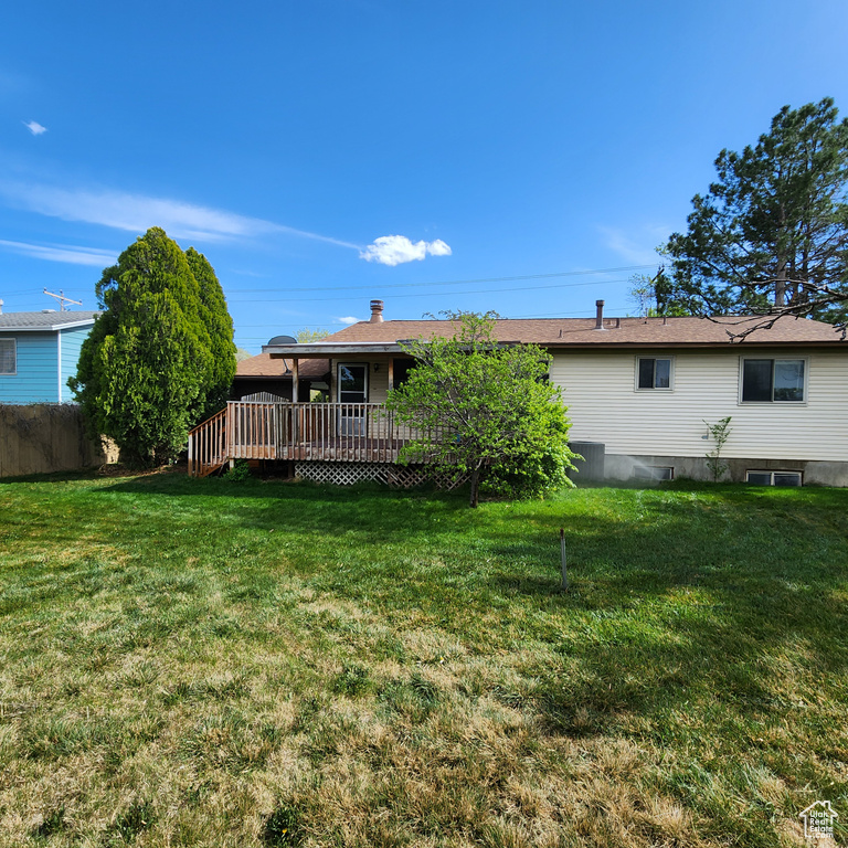 Rear view of house with a yard, fence, and a wooden deck