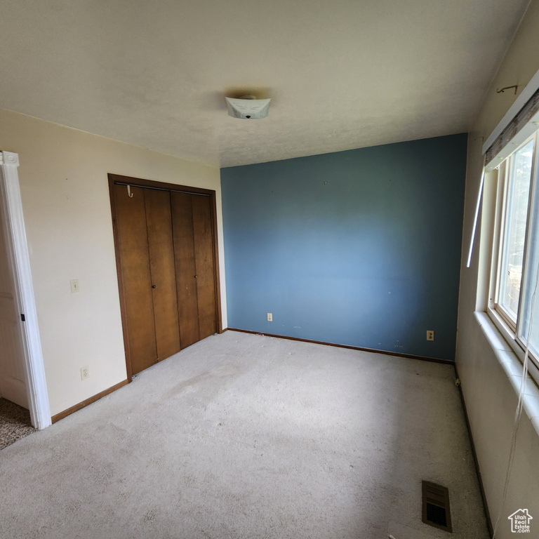 Unfurnished bedroom featuring baseboards, a closet, carpet floors, and visible vents
