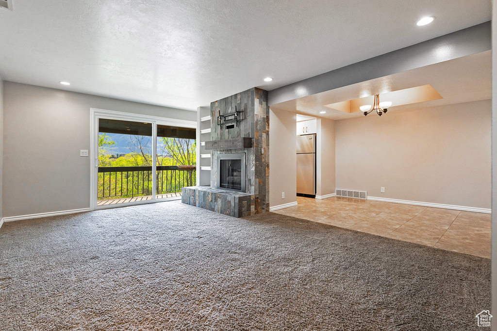 Unfurnished living room featuring carpet flooring, a notable chandelier, baseboards, and visible vents