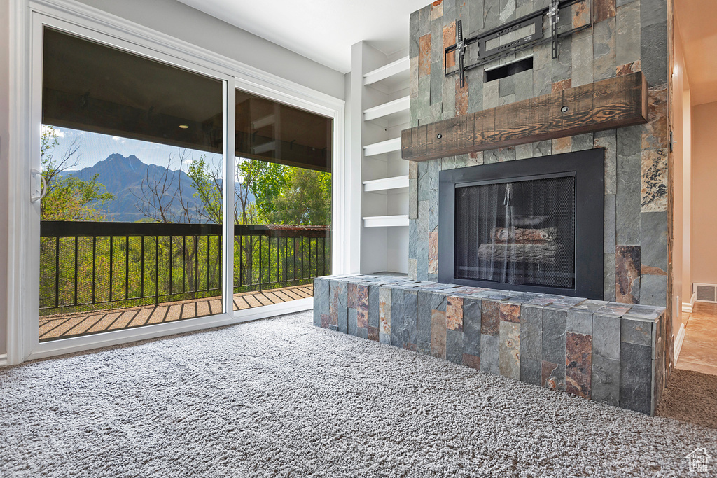 Exterior space with carpet floors, built in features, a tile fireplace, visible vents, and a mountain view