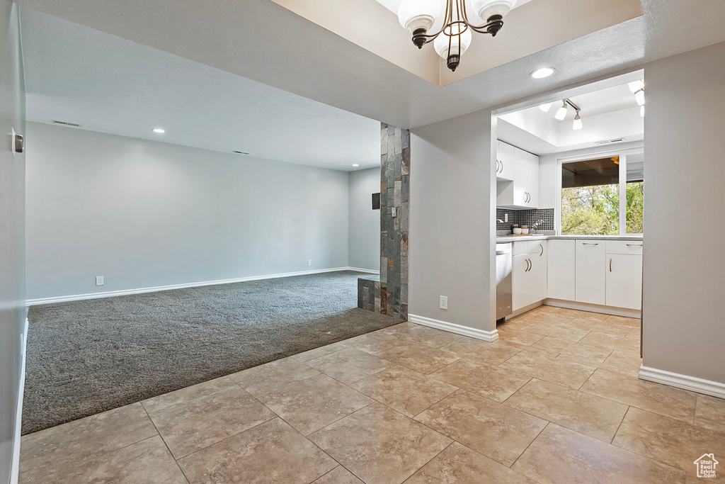 Interior space with baseboards, recessed lighting, a notable chandelier, and light carpet
