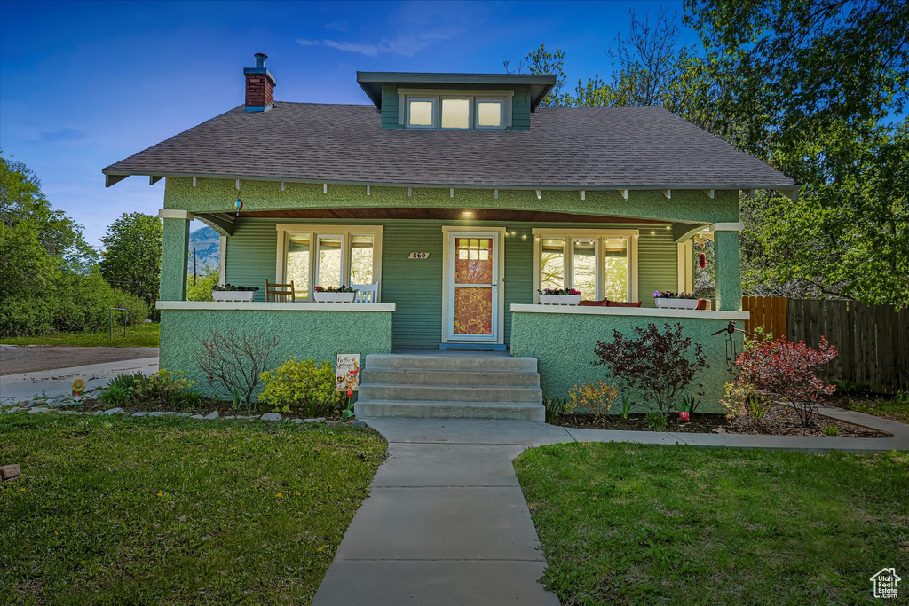 View of front of house with fence, a shingled roof, a porch, and a front lawn