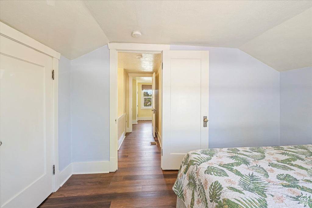 Bedroom featuring wood-type flooring, baseboards, visible vents, and lofted ceiling