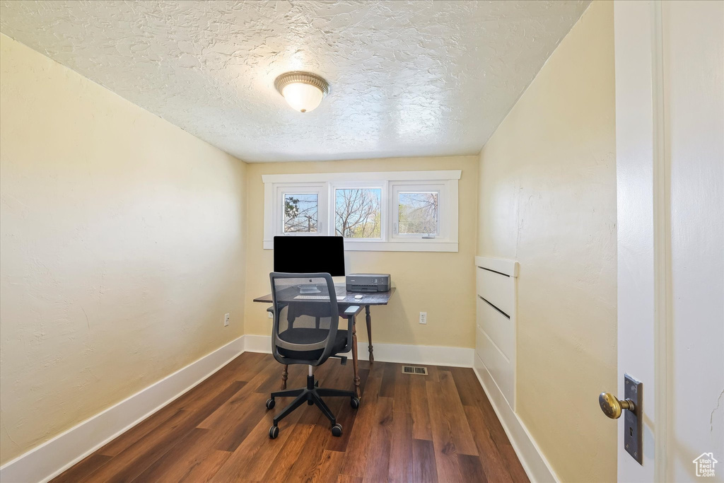 Home office featuring baseboards, a textured ceiling, and wood finished floors
