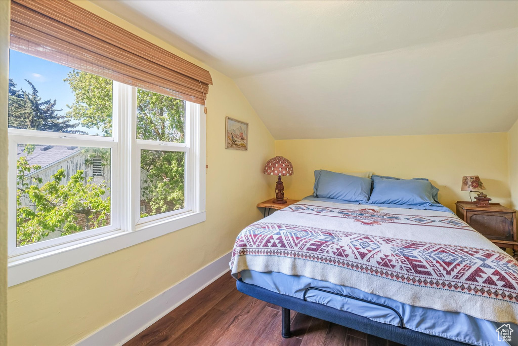 Bedroom with wood finished floors, baseboards, and lofted ceiling