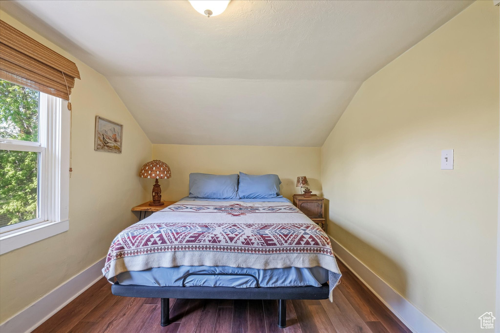 Bedroom featuring vaulted ceiling, multiple windows, and wood finished floors