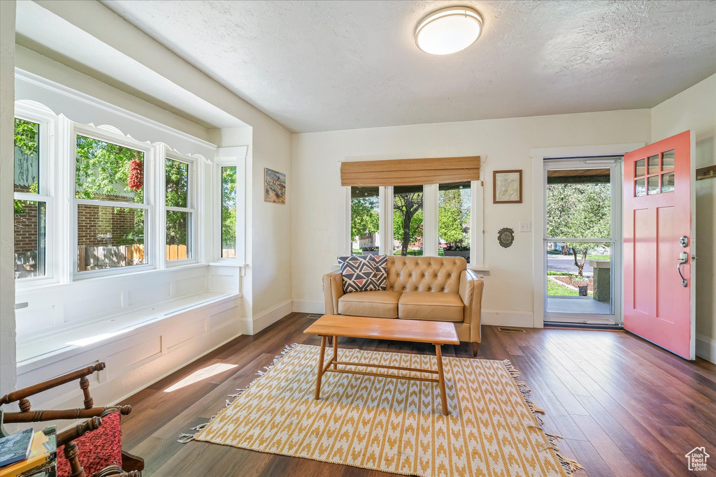 Living room with baseboards, a textured ceiling, and dark wood finished floors