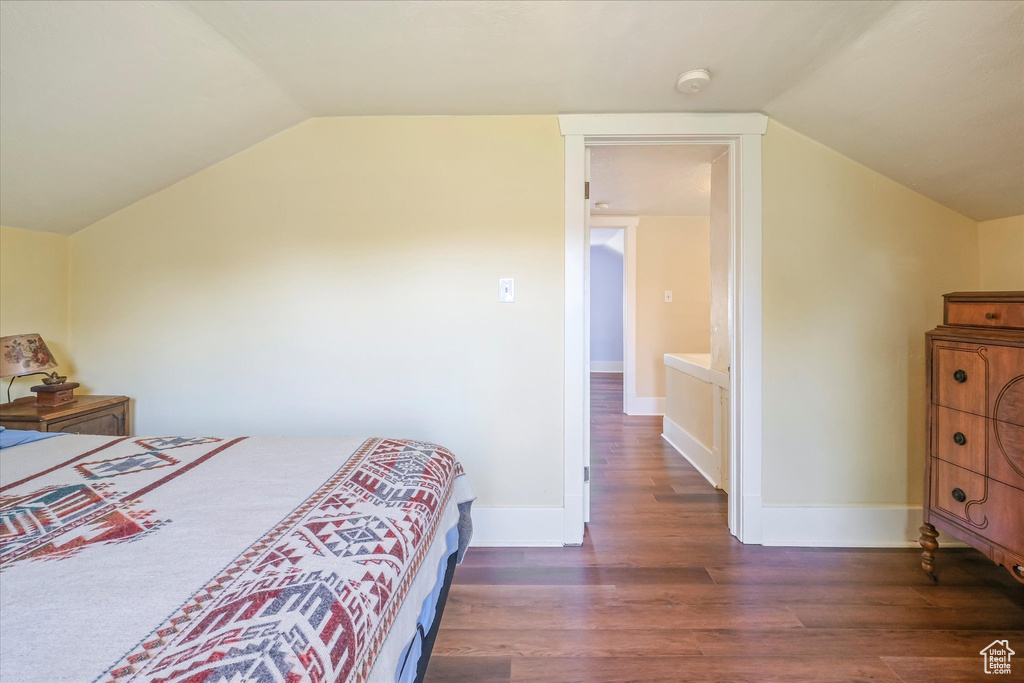 Bedroom featuring baseboards, wood finished floors, and lofted ceiling