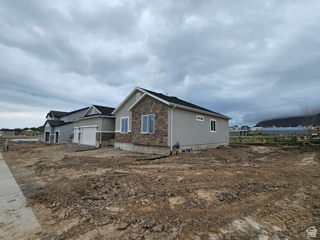 View of property exterior featuring an attached garage, fence, and stone siding