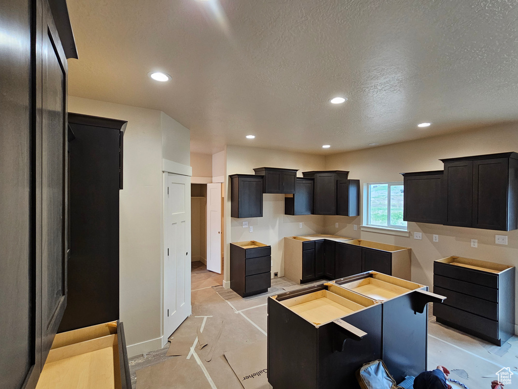 Kitchen featuring dark cabinets, baseboards, recessed lighting, and a textured ceiling