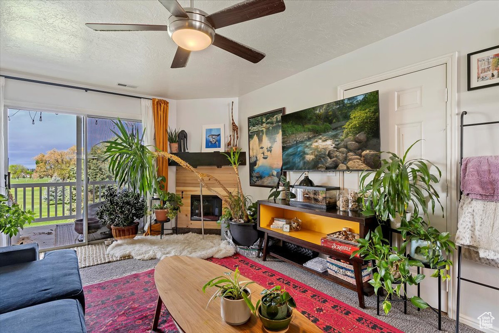 Living room with a ceiling fan, a textured ceiling, visible vents, and carpet