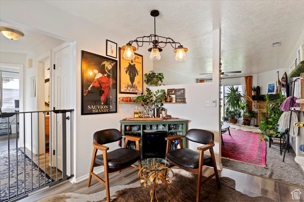 Dining space with a textured ceiling, wood finished floors, and visible vents