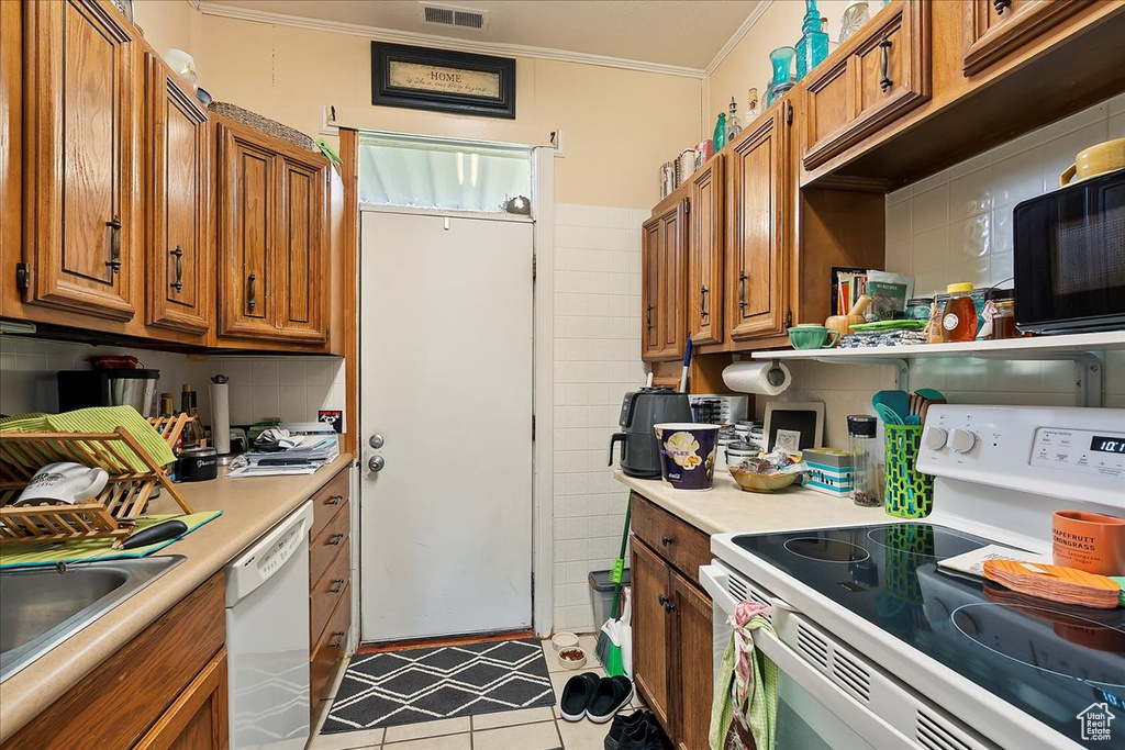 Kitchen with white appliances, brown cabinets, ornamental molding, and light countertops