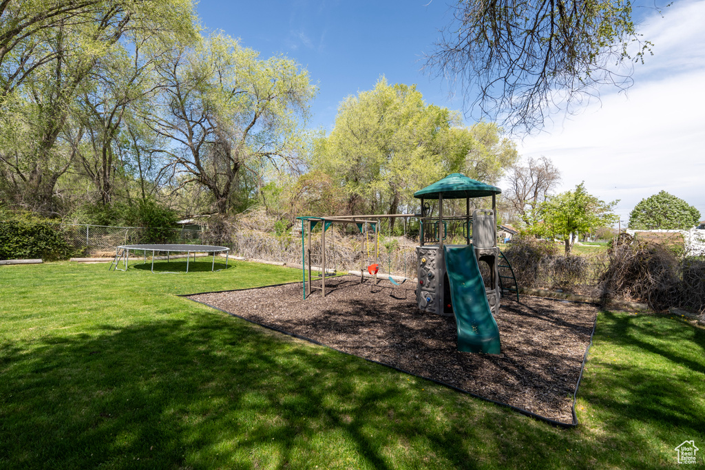 Community play area featuring fence, a trampoline, and a lawn
