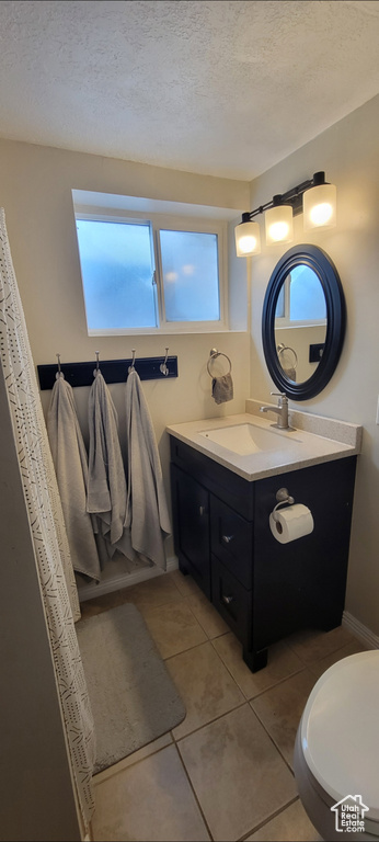 Full bathroom with tile patterned flooring, vanity, toilet, a textured ceiling, and baseboards
