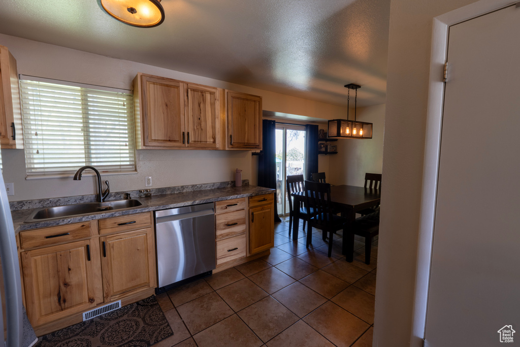 Kitchen with appliances with stainless steel finishes, hanging light fixtures, a sink, dark tile patterned floors, and visible vents