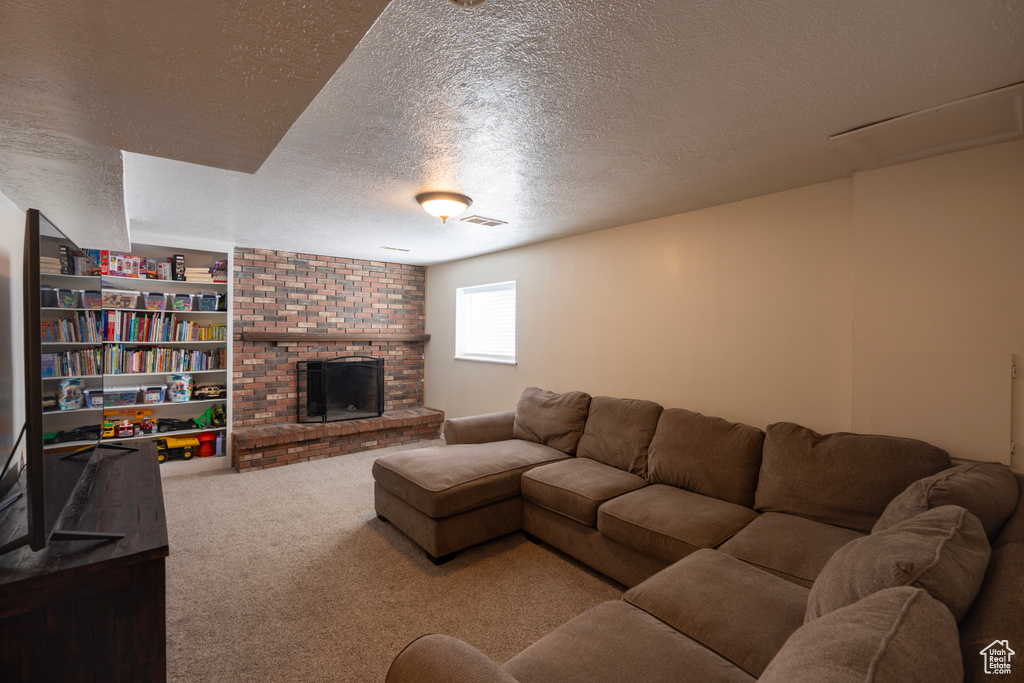 Carpeted living room with a fireplace, a textured ceiling, and visible vents