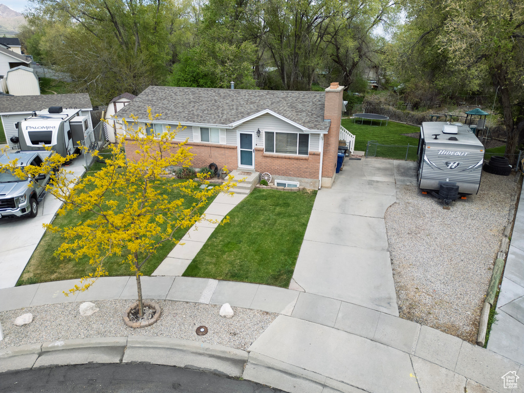 View of front of house featuring brick siding, a front lawn, a chimney, and concrete driveway