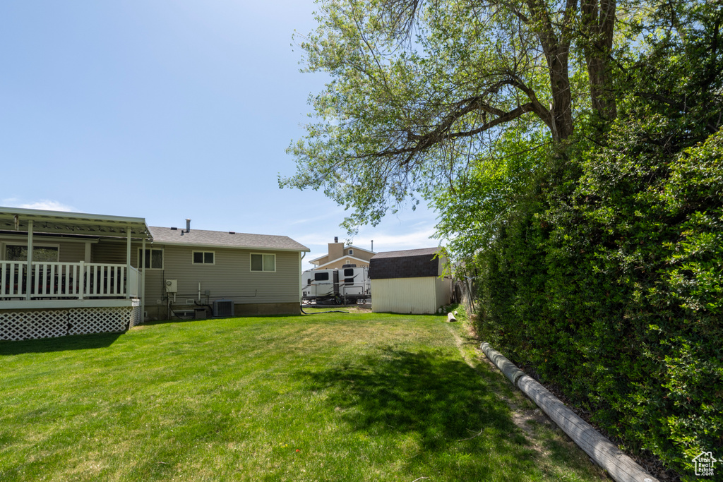 View of yard featuring an outdoor structure, a wooden deck, and a storage shed