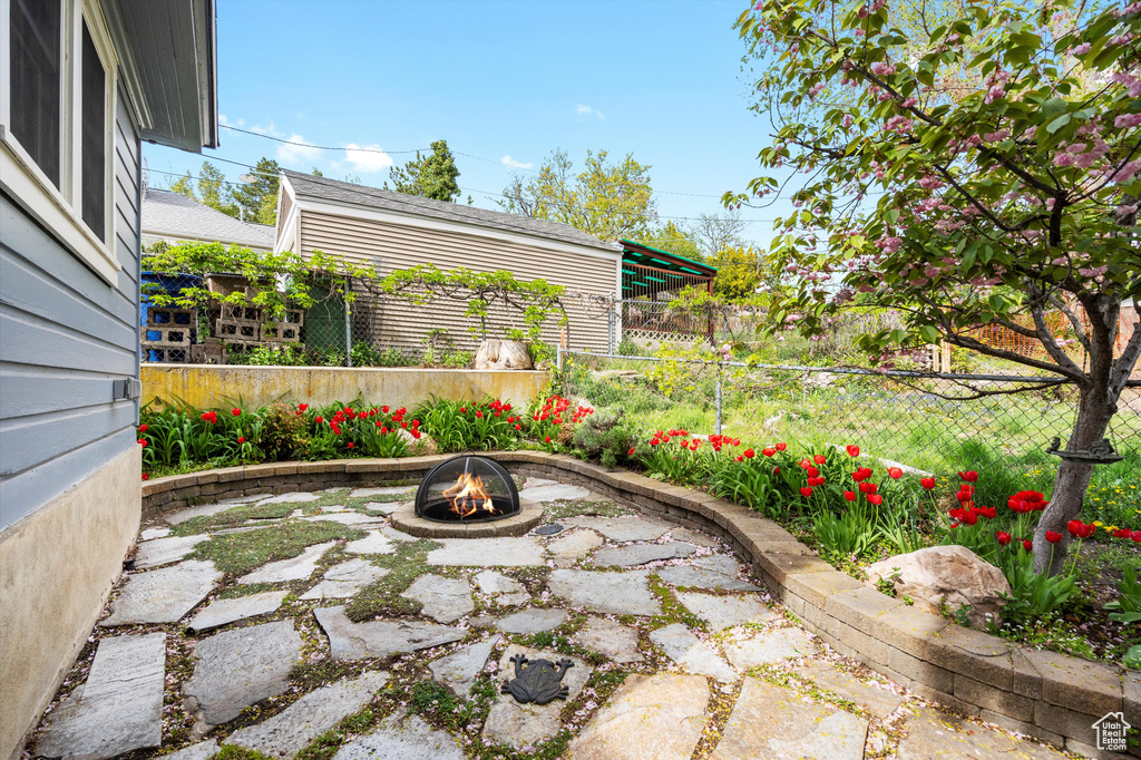 View of patio with an outdoor fire pit and fence