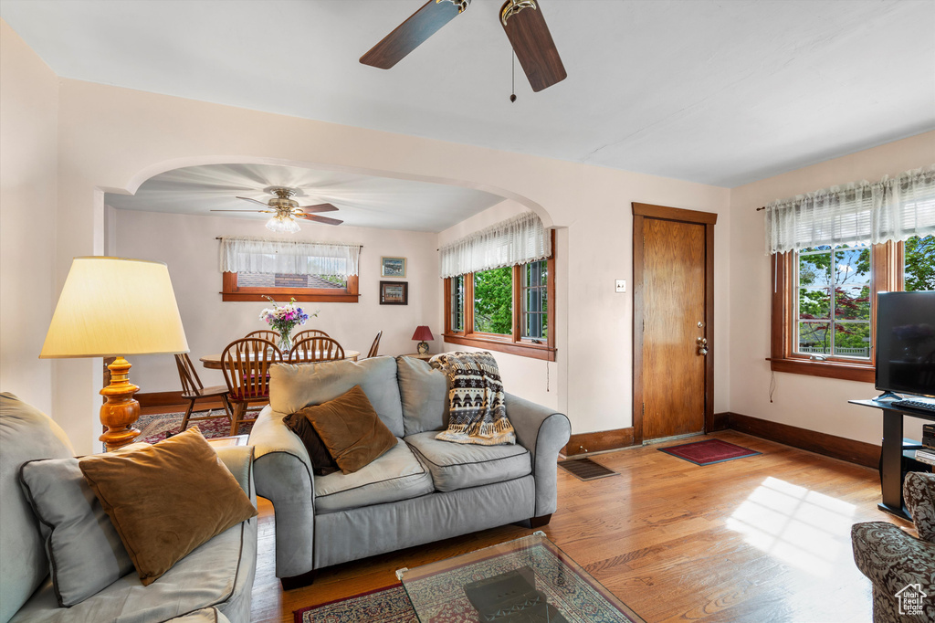 Living room with baseboards, arched walkways, ceiling fan, and wood finished floors