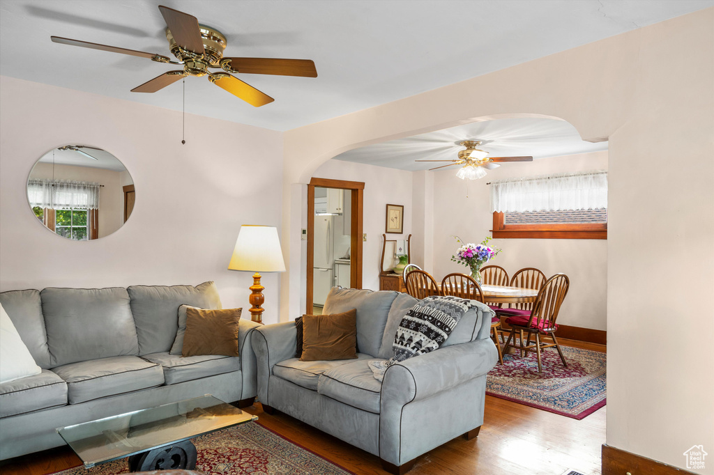Living room with baseboards, arched walkways, ceiling fan, and wood finished floors