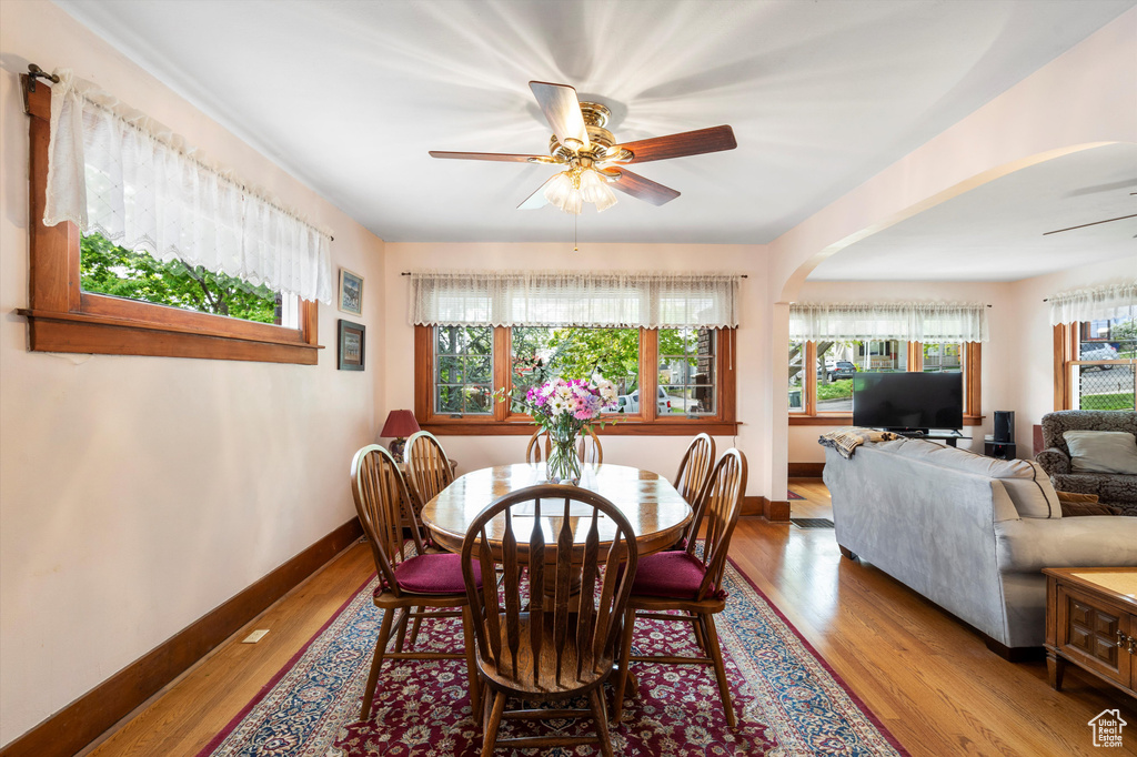 Dining room featuring arched walkways, ceiling fan, baseboards, and wood finished floors