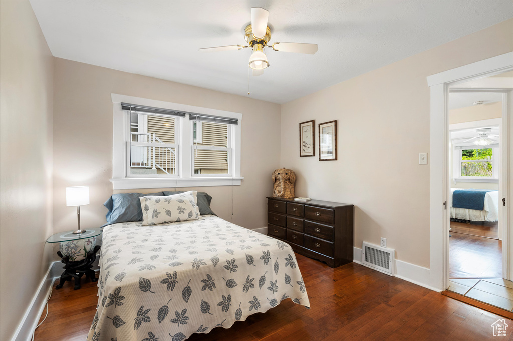 Bedroom with a ceiling fan, baseboards, visible vents, and dark wood-style floors