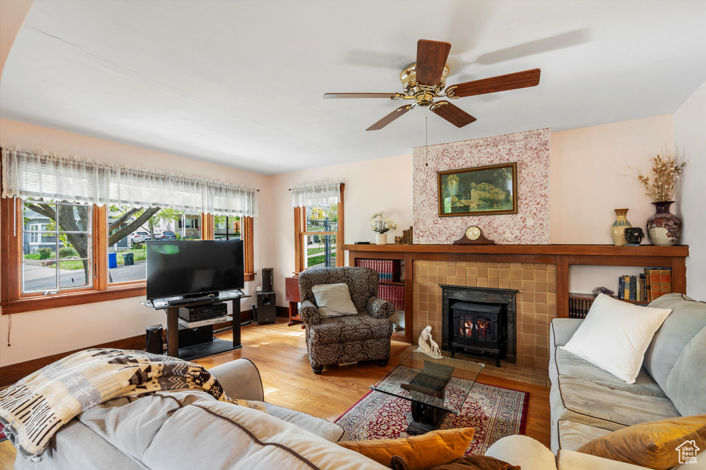 Living room with ceiling fan, wood finished floors, and a wood stove