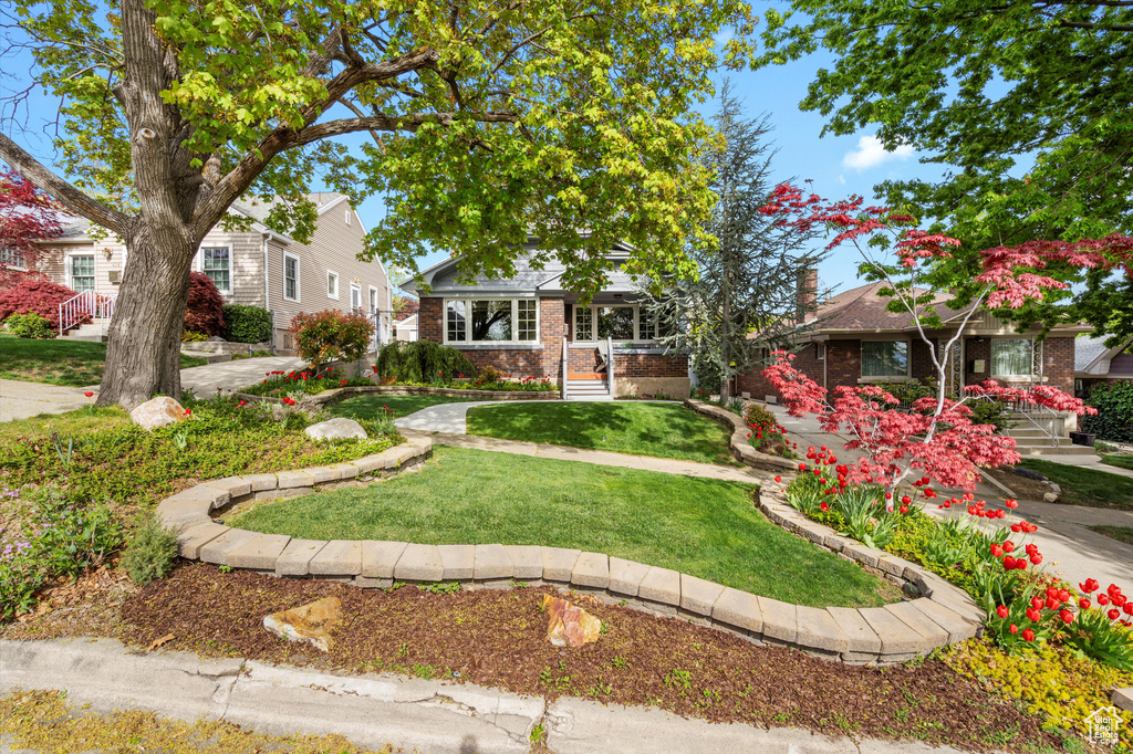 View of front facade with brick siding, a chimney, and a front lawn