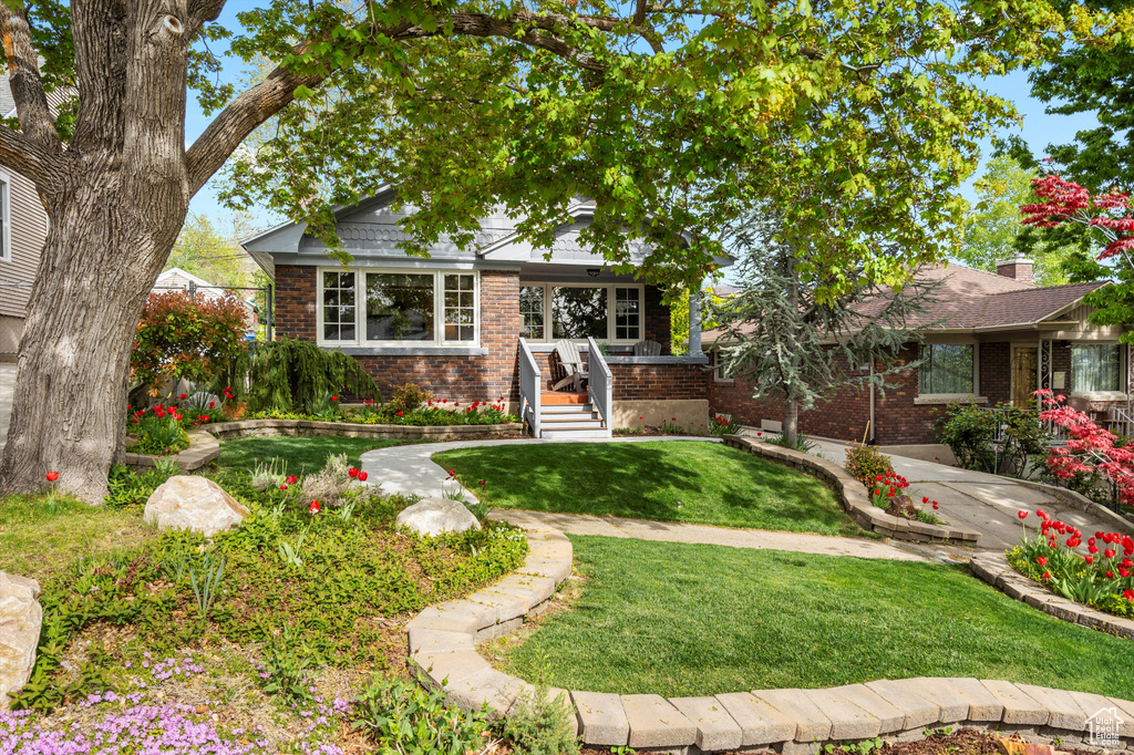 Bungalow with a front yard and brick siding